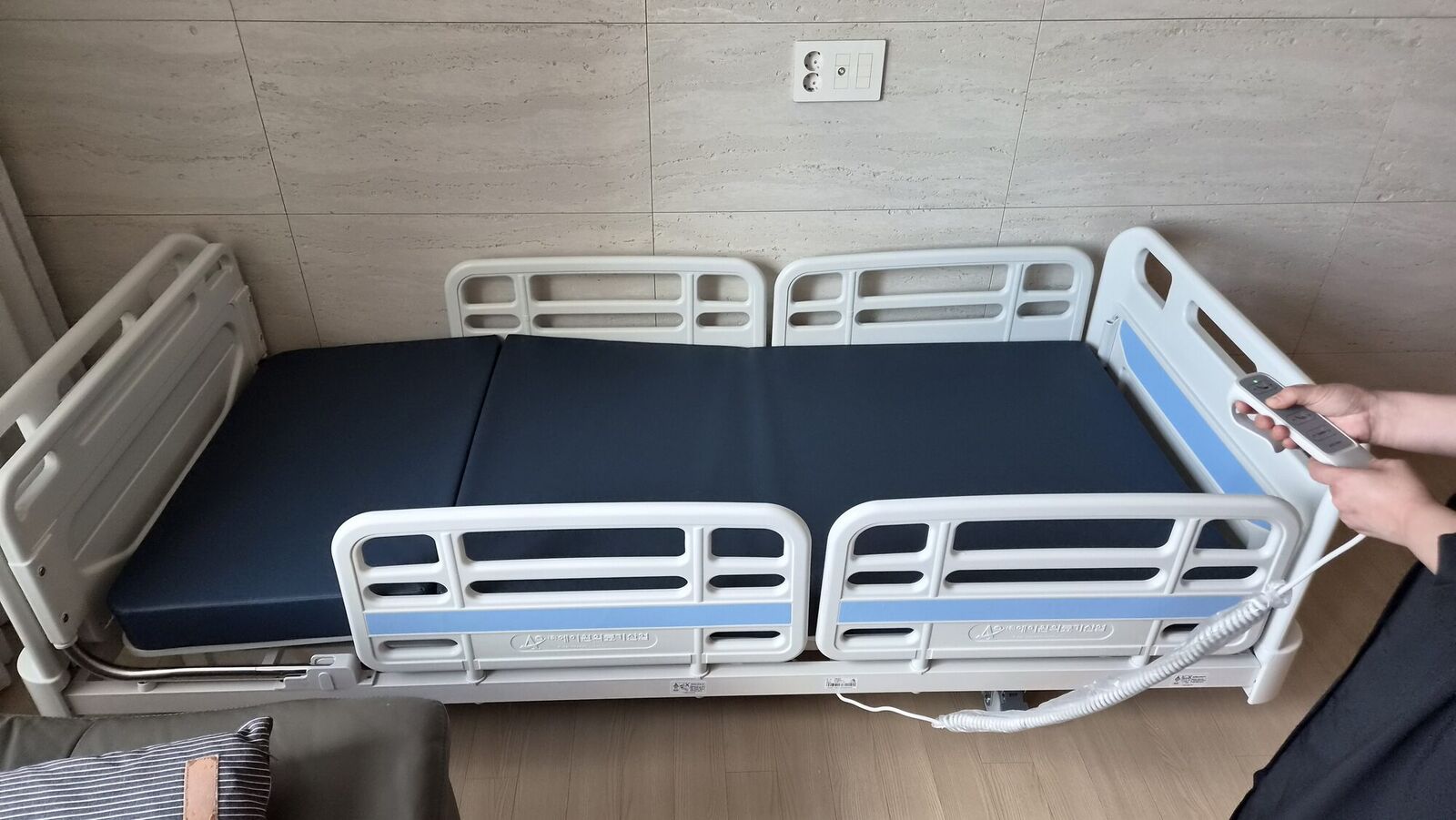 광주남구 재가복지와 함께 안내하는 복지용구 참고사진 - 안전난간을 올린 전동침대와 리모컨